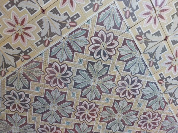 Old tiles with flower pattern with a touch of pink, yellow and green and matching borders