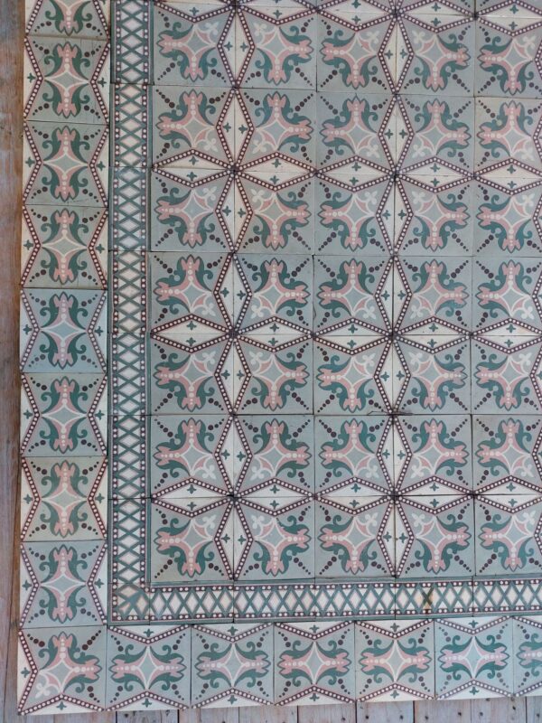 Old floor tiles with double border and dotted star pattern in shades of pink and green