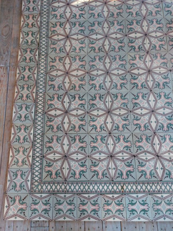 Oude keramische art-nouveau tegelvloer met originele dubbele boord in tinten van oud roos en groen