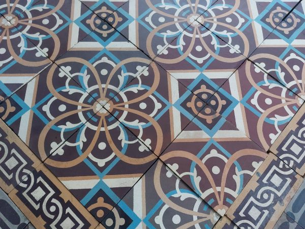 Zeldzame antieke keramische vloer met bloempatroon en dominante kleuren oranje, blauw en bruin