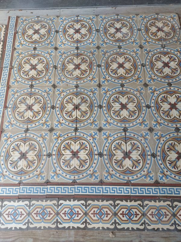 Reclaimed encaustic floor with original border tiles in a cool color palette