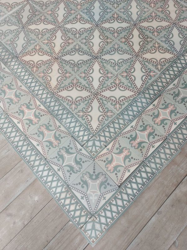 Antieke keramische vloer met originele boordtegels in tinten van groen en roos