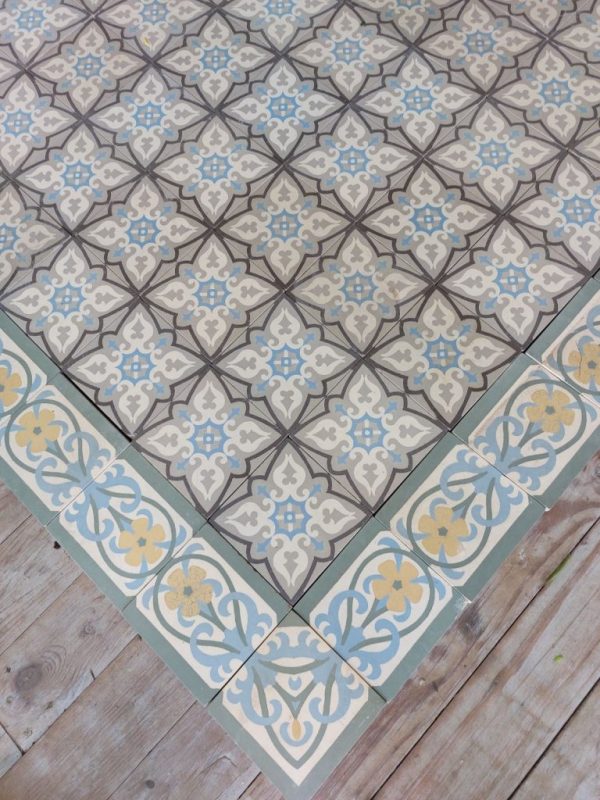 The floor showcases a single tile with a geometrical design in a cool color pallete with a matching single border