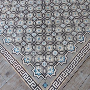 Antique vloer met klassiek geometrisch patroon en koel kleurenpalet met bijhorende randtegels