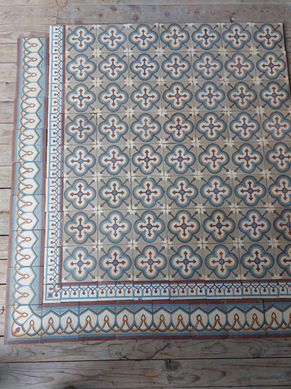 Oude tegels met geometrisch patroon en een dubbele rij randtegels met blauw, rood en grijs als dominante kleuren