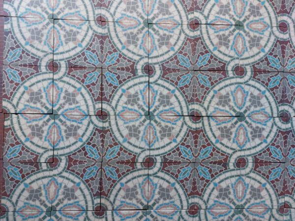Reclaimed mosaic tiles with a vegetal and geometric pattern in a warm color palette with pink, blue and burned red as dominant colors