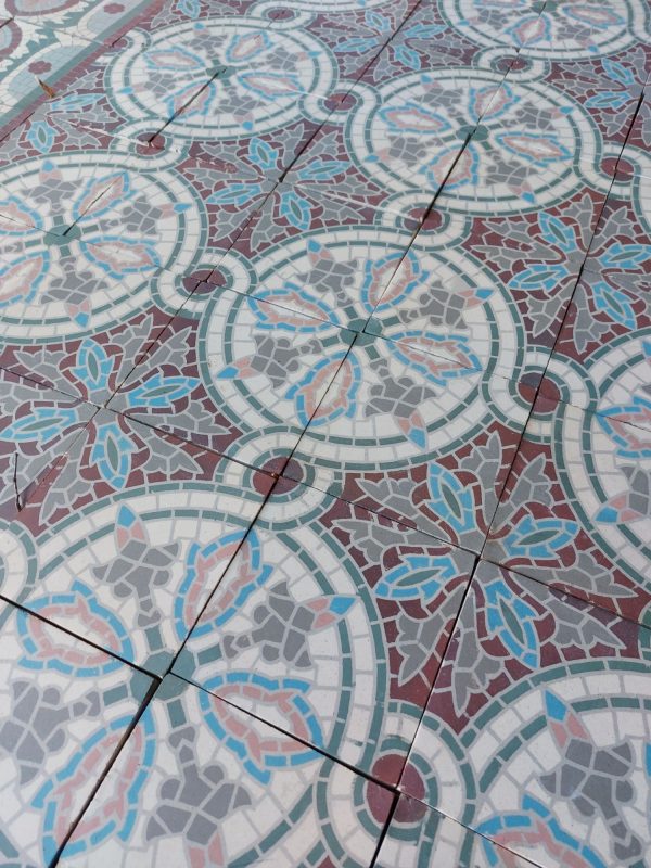 Antieke vloertegels in een fleurig mozaïekpatroon met roos, bordeaux, blauw en wit als dominante kleuren