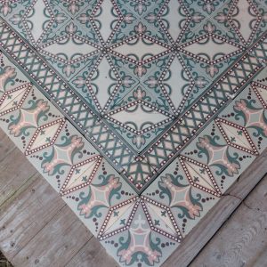 Art-Nouveau encaustic floor with a dotted star pattern in a palette of soft pink and green with original border tiles