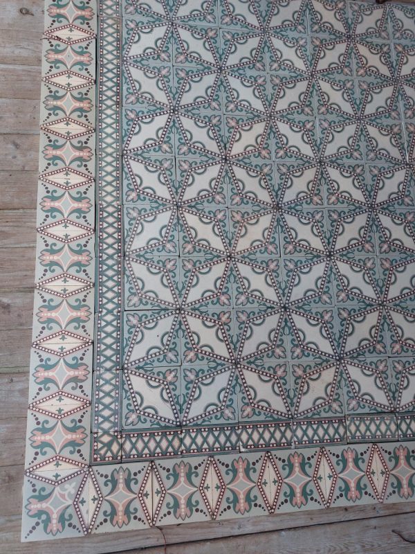 Art-Nouveau reclaimed floor with a dotted star pattern in a palette of soft pink and green with original border tiles