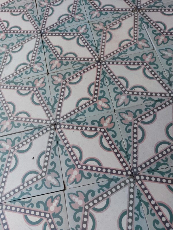 Reclaimed floor tiles with a dotted star pattern in a palette of soft pink and green
