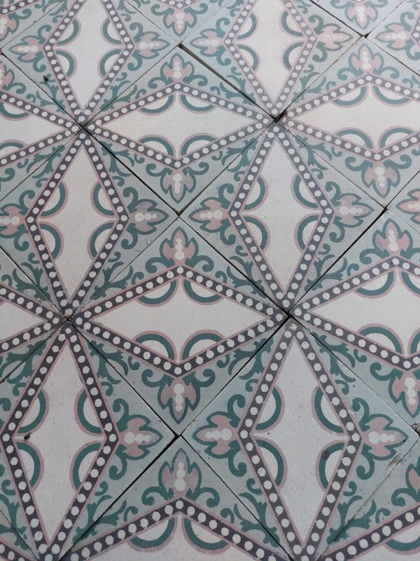Antique floor tiles with a dotted star pattern in a palette of soft pink and green