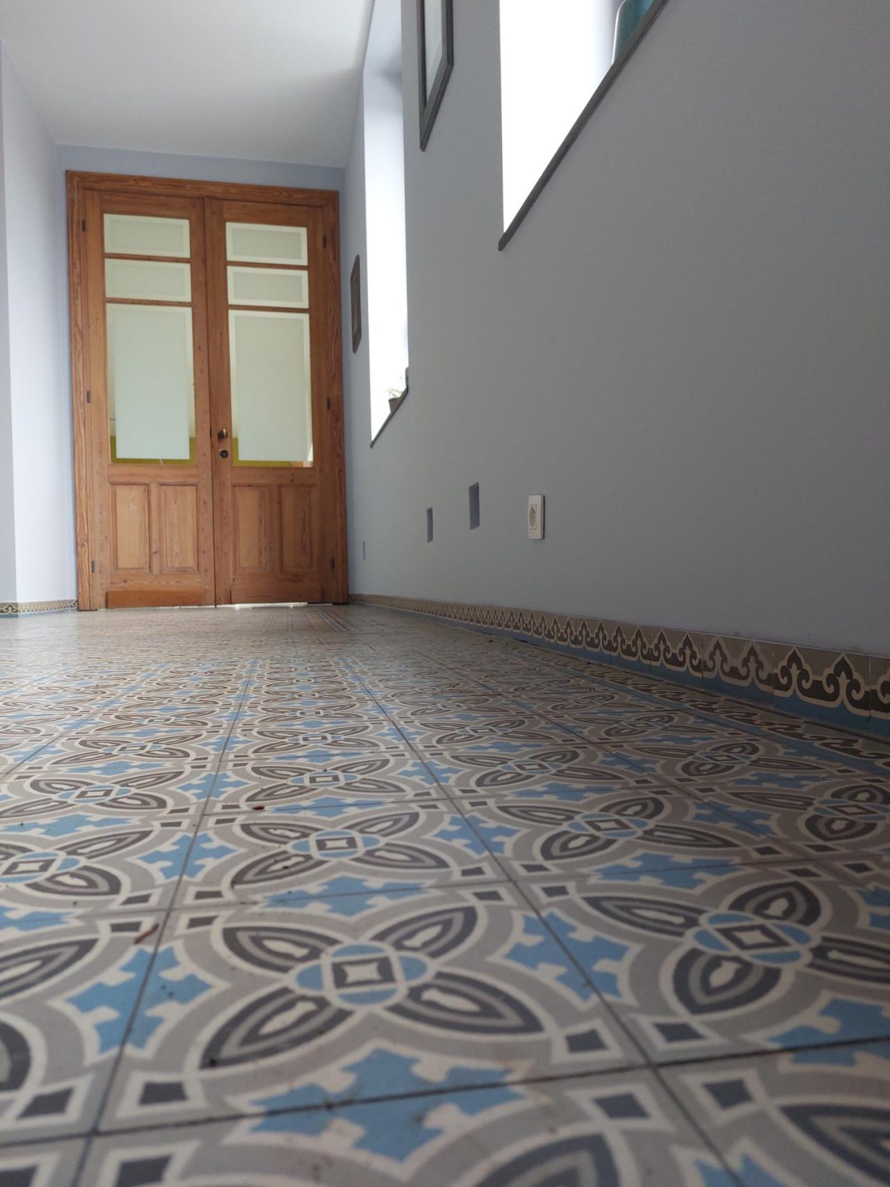 gang antieke vloertegels in blauw en grijstinten met sterk geometrisch patroon