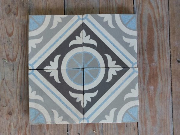 A four tile geometric motif in different shades of grey with blue