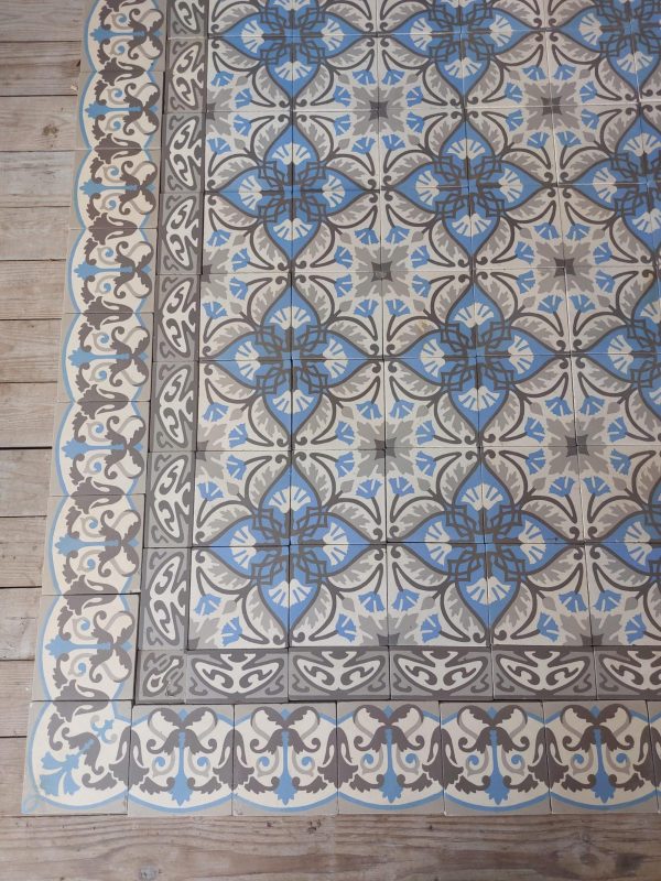 Oude keramische patroontegels met bladmotief en bijhorende randtegels met blauw en grijs als dominante kleuren